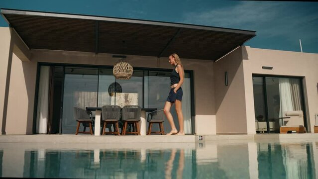 Young attractive blonde woman walking in a luxurious designer pool villa
