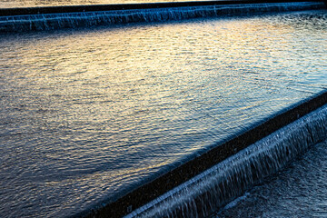 A shallow, urban waterfall, reflecting sunset colors. © Margaret Burlingham
