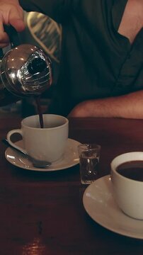 Pouring native Philippine coffee or kape bisaya from a classic french press at a rustic cafe