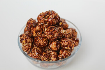 Chocolate popcorn, in transparent glass bowl, isolated on white background