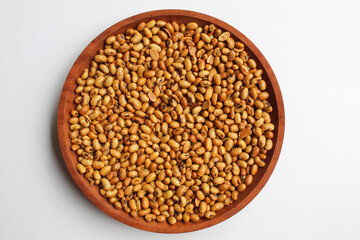 Fried soy bean on wooden plate, isolated on white background, flat lay or top view