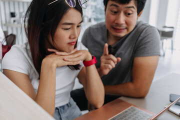 Asian man teaching and recommending something to woman, Both learning from laptop.