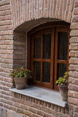 Rustic brick wall with a wooden window and potted plants on the windowsill in a charming setting