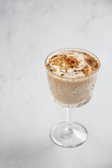 Close-up vertical shot of a creamy beverage in a decorative glass on a marble surface