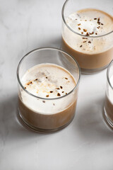 Vertical shot of glasses of creamy coffee with foam on a white marble surface