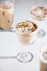 Vertical shot of various iced coffee drinks in elegant glasses on a white background