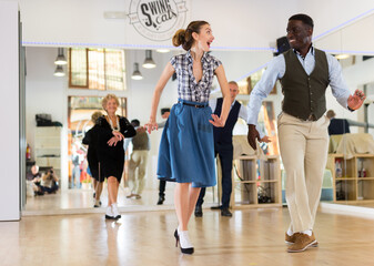 Man and woman performing jazz dance in dancing room