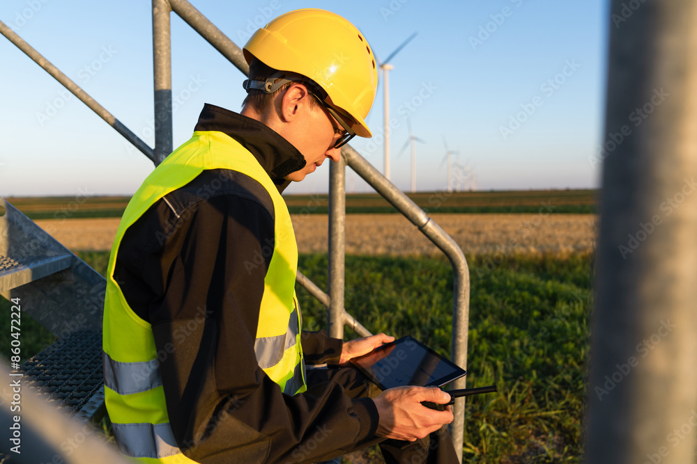Poster engineer with digital tablet works on a field of wind turbines