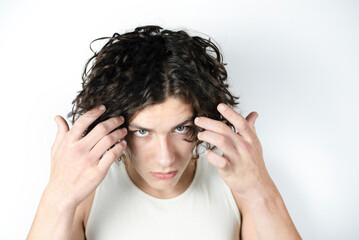 A young teenage boy looks up and down in disbelief, picks up his long hair from eyes. A sad teenage boy has problems communicating with adults and peers