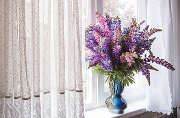 A bouquet of flowering Lupines in a vase (Lupinus polyphyllus). Flowering field large-leaved lupines or garden lupines in early summer, close-up with selective focus.