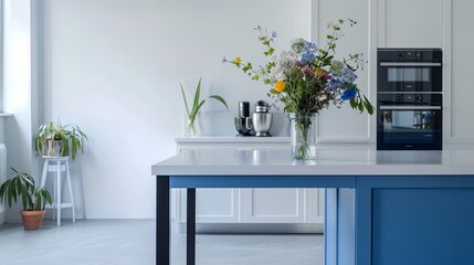 Bright, Scandinavian-style kitchen features a blue island table and modern appliances. The white walls and floor create a clean and airy atmosphere, while the vase of flowers adds a touch of nature.