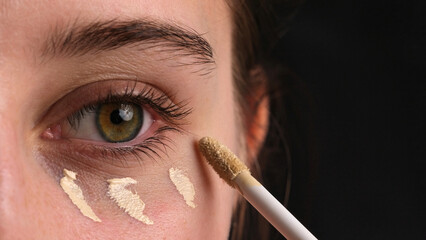 Close-Up Shot Of A Girl Applying Concealer Under Her Eyes And Makeup Foundation On Her Eyelids