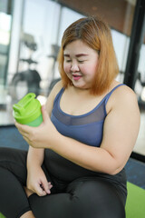 Obese asian woman dieting Weight loss in sportswear drink healthy drink. Sporty asian fat female drinking green Healthy juice After Exercise wellness health