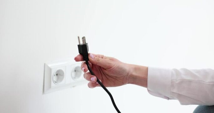 Woman tries to wire wrong plug to socket on white wall in office room. Lady fails connecting appliance to electrical network. Technical details