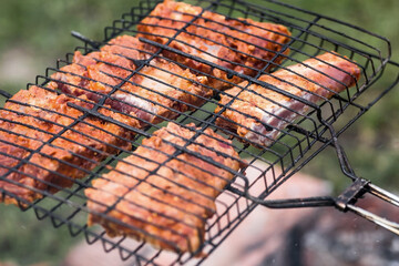 Barbecue at the cottage. May holidays. Barbecue in nature. The process of cooking meat on the grill, close-up. Barbecue of pork ribs on the grill.