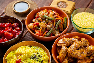 Couscous with dried fruits, chicken in spices and vegetables stewed on the table. Horizontal photo.
