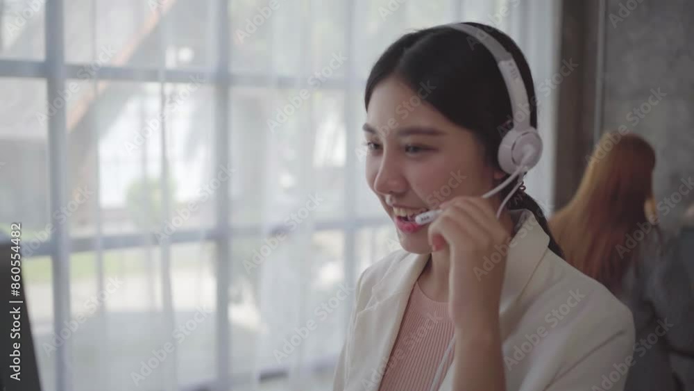 Aufkleber friendly call center agent with a headset smiling and talking to customers in a modern office with l