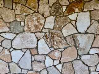 A decorative exterior rock wall features intricate patterns and natural textures, blending rugged stones into a visually appealing and durable structure that enhances the aesthetic of outdoor spaces.