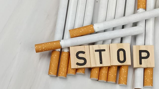 tas de cigarettes, vue du dessus, avec le mot Stop &eacute;crit en lettres en bois dessus.