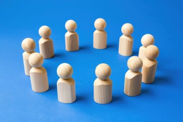 Obraz premium Wooden figures in a circle on a blue background: various sizes and positions of people in the circle