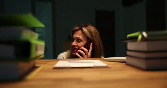 Scared woman calls police by phone explaining dangerous situation. Terrified employee feels afraid to stay alone in dark office in late evening
