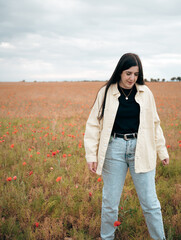 A girl walks through the poppy field at sunset