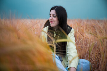 Young woman enjoying a sunny day on the meadow. Wheat fields
