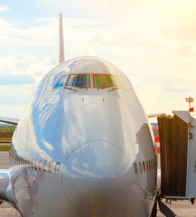 large jumbo jet airliner stands at the tunnel at the airport before departure, sunny bright day.
