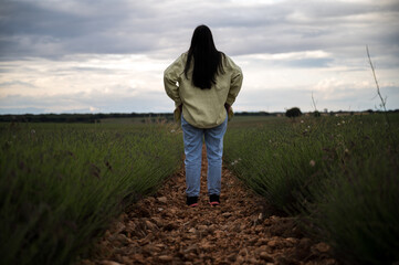 Young woman looking at lavender crop field and flowers