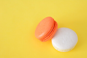 two orange and white macarons are on a yellow table 