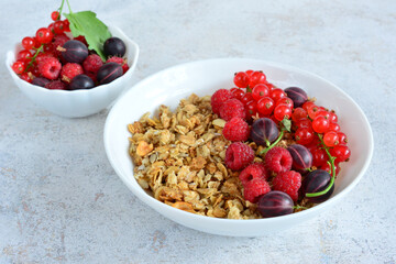 a bowl of granola with berries next to a bowl of raspberries 