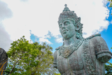 The statue of Lord Vishnu against the backdrop of a cloudy blue sky at the Garuda Wisnu Kencana...