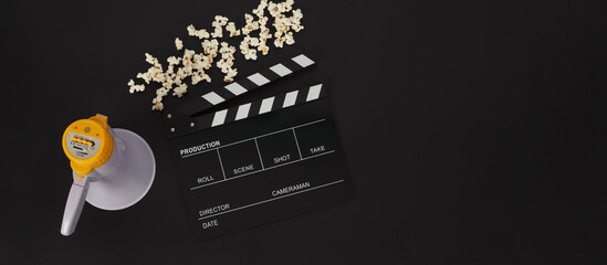 Clapper board and megaphone and popcorn on black background.
