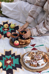 Enjoy a serene outdoor picnic with pastries and apples laid out on a chic blanket in a cozy setting. Vertical