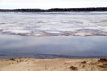Spring flood, river with remnants of ice, melting ice, landscape river ice spring, thawed dangerous ice.