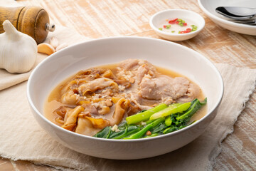 Flat Noodles with Marinated Pork and Collard greens in Gravy Sauce in white plate