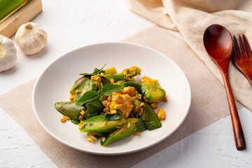 Stir fried Long Green Eggplant with Eggs and Sweet Basil leaf in white plate.