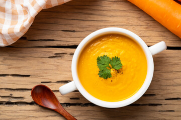 Bowl of tasty Creamy Carrot Soup with vegetables on wooden table,Healthy food.Top view