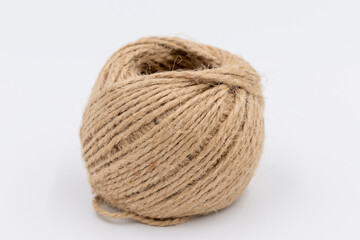 Close-up view of roll of brown jute twine for crafting lying on white background. Soft focus. Hobbies and craft materials theme.