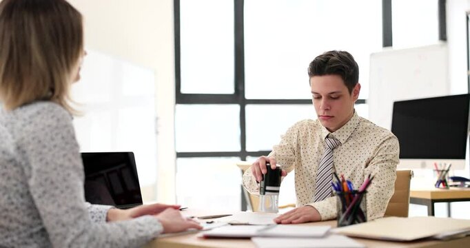 Clerk puts stamp on customer document in company office slow motion. Manager approves official contract papers for client at workplace