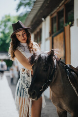 Obraz premium Young woman in a cowboy hat lovingly petting a horse outdoors on a bright and sunny day. Connection with nature and animals.