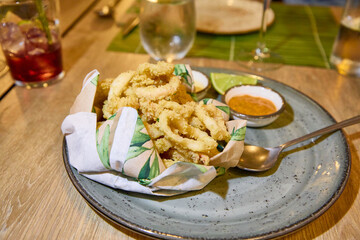 Gray plate with rings of squid, breaded and fried, typical food of Andalusia (Spain, Europe) on wooden table of restaurant ready to eat