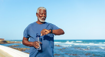 Active senior African American man checking time by the sea