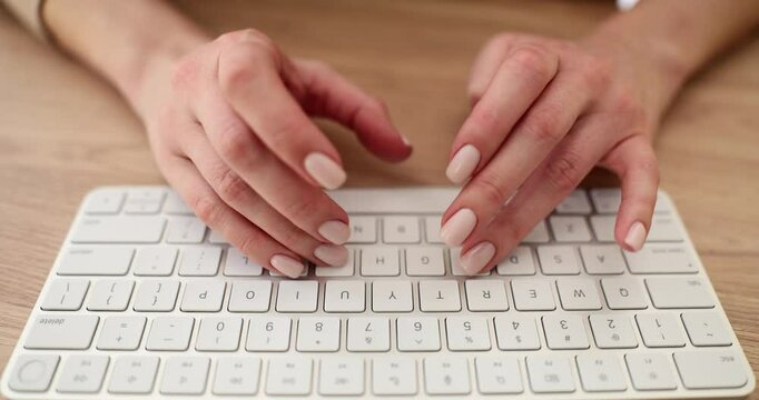 Woman types on stylish wireless keyboard at wooden table slow motion. Lady uses contemporary computer accessory in office. Digital technology