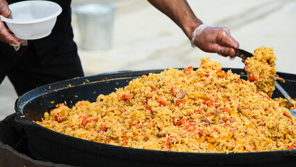 Cooking traditional oriental pilaf in a cauldron in nature