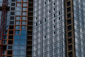 Fototapeta premium Close-up side view of blue glass wall of modern skyscraper building under construction. Copy space. Abstract construction background. Housing development theme.