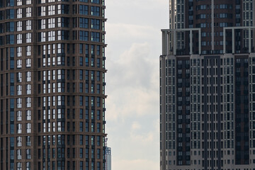Fototapeta premium Side view of frame between dark modern office or residential buildings. Middle section. Copy space. Grey rainy cloudy sky. Soft focus. Housing development theme. 