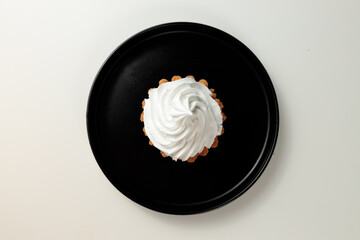 cake basket with protein cream in a black round plate on a white background