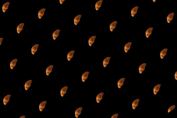 Pattern of baked croissants with a black background. Delicious pastries