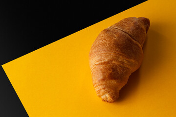 Croissant on a yellow and black background. Delicious pastries on a yellow-black background